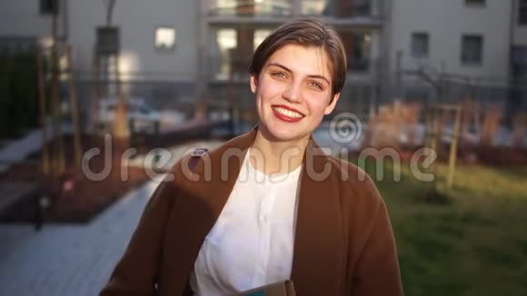 一位微笑的年轻房地产经纪人在一座新城市建筑的院子里的肖像幸福的女人房地产视频的预览图