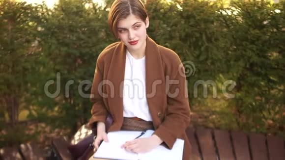 短发女孩穿着棕色外套有笔记本和摘要一个学生正在准备考试而坐在视频的预览图