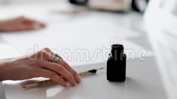 女人手里拿着一支书法笔浸在墨水瓶里视频的预览图