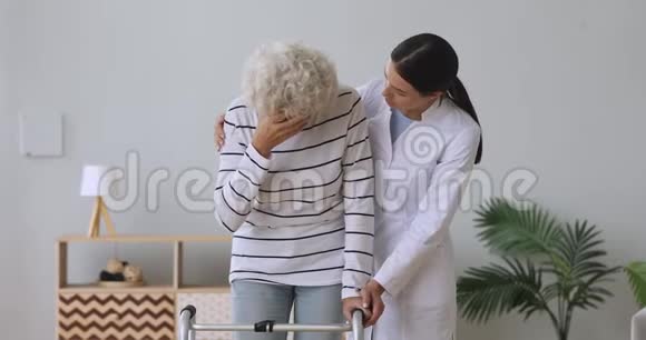 年轻女性照顾者支持安慰悲伤残疾老奶奶病人视频的预览图
