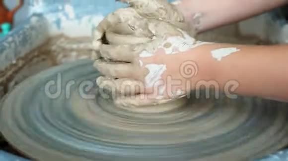 小女孩在陶轮上塑造一个泥碗肮脏的孩子手视频的预览图