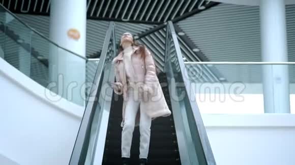 美丽的年轻女孩在扶梯上的购物中心自由跳舞感觉很快乐不害羞休息时间视频的预览图
