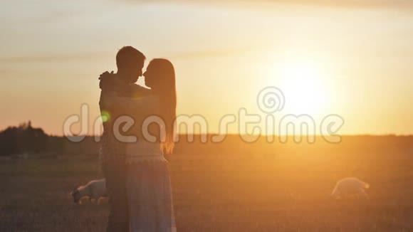 情侣在日落和山羊背景下拥抱情侣的剪影视频的预览图