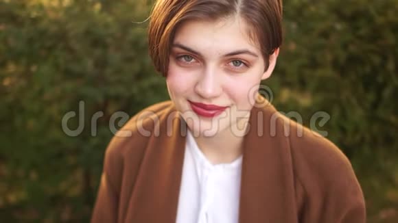 一个美丽的年轻女孩的肖像剪短的发型和白牙的微笑快乐女人户外肖像视频的预览图