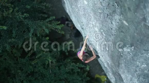 顶景女子攀岩者在艰难的运动路线上攀爬寻找寻找到达和抓住持有视频的预览图