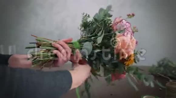 专业的花艺女孩为鲜花做插花系绿色丝带花束花艺店视频的预览图