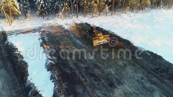 推土机铲平沙子在冬天筑路砍伐森林建设发展新公路空中侧景视频的预览图