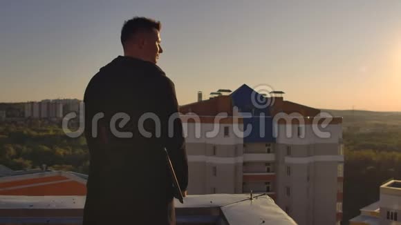 日落时分一个手提电脑的人走在屋顶上日落时分从高处看城市视频的预览图