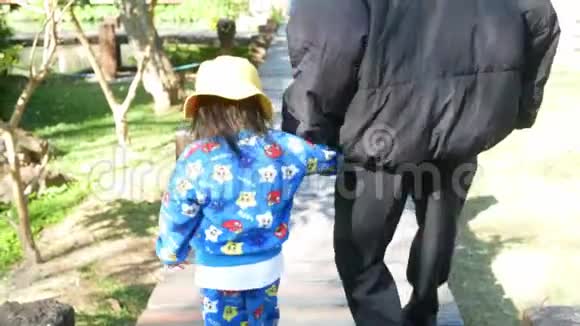 快乐的亚洲祖父牵着孙女的手一起走在花园里的木桥上视频的预览图