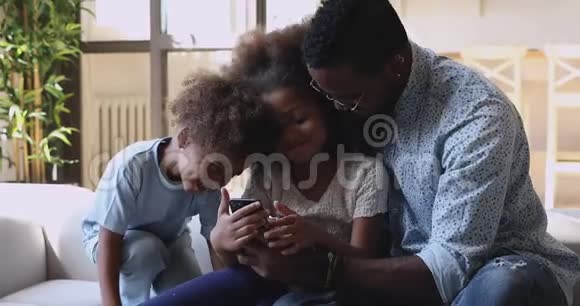 快乐的非洲爸爸和小孩在玩手机应用程序视频的预览图
