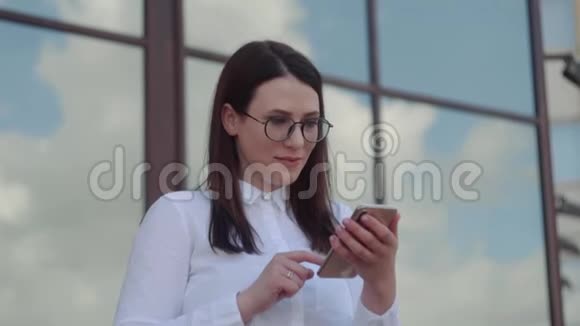 商务女性穿着白色衬衫使用智能手机并在办公室附近发短信按摩的肖像慢动作镜头视频的预览图