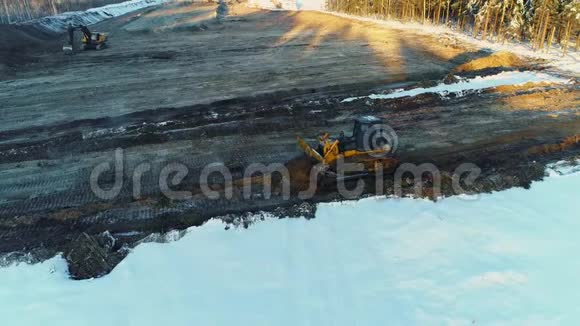 两台推土机平沙在冬天修一条路砍伐森林建设发展新公路空中侧景视频的预览图