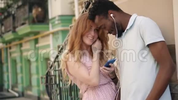 年轻夫妇在街上用耳机听音乐视频的预览图