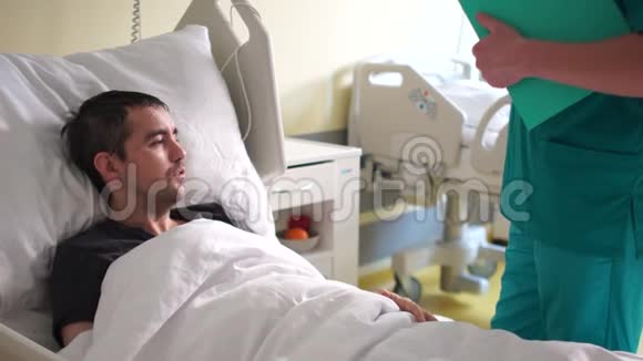 事故后的康复一个年轻人躺在床上一个医生站在他旁边一个病人在说话视频的预览图
