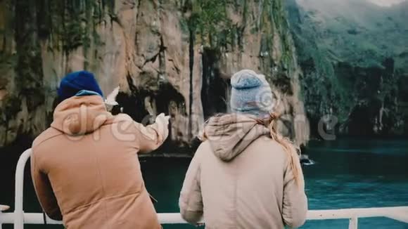 年轻时尚夫妇站在船上看着冰岛经过的岛屿视频的预览图