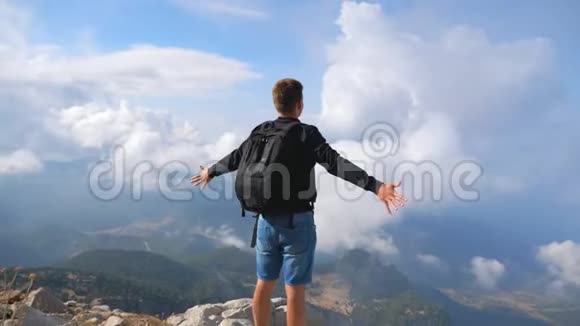徒步旅行者背着背包站在山边举起双手享受自由旅行期间男士积极休息视频的预览图