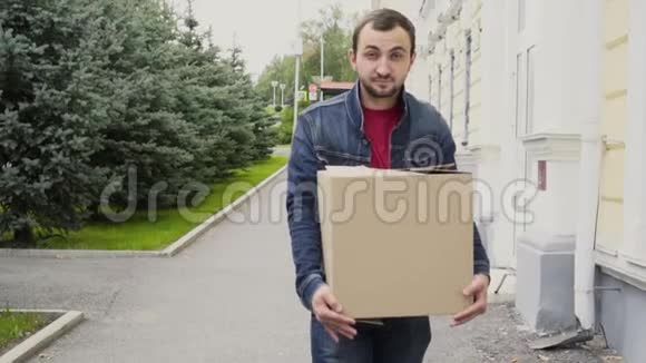 一个英俊的男人拿着一个纸板箱在户外散步视频的预览图