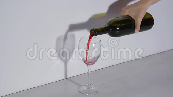 概念镜头在灰色背景下将红酒倒入玻璃杯中视频的预览图