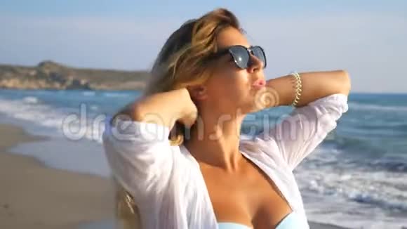 戴着太阳镜的美丽女士微笑着玩着她的头发漫步在海岸边自由女神像视频的预览图