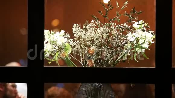 玻璃花瓶里放着一束白花从咖啡厅窗口观看视频的预览图
