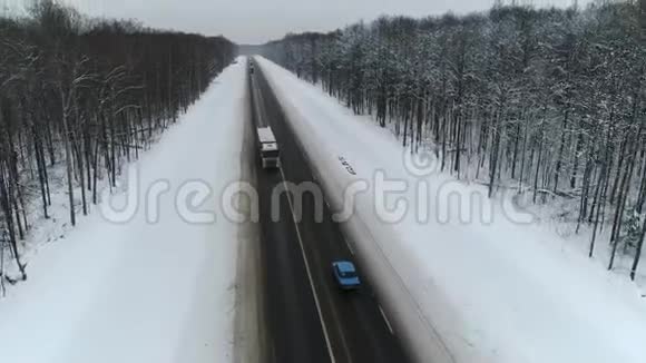 蓝色复古车和卡车在冬天的森林里骑在一条路上空中观景视频的预览图