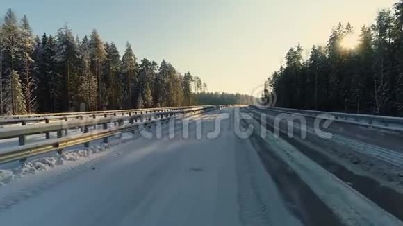 在美丽的阳光明媚的冬季常绿森林里车辆在高速公路上行驶视频的预览图