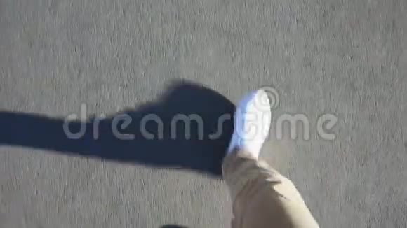 一名男子光天化日之下穿着白色运动鞋行走在人行道上视频的预览图