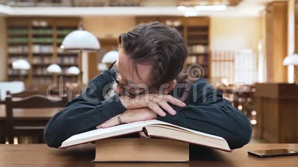 可爱的青少年学童醒来时他们疲惫的尊敬的祖父睡在图书馆的书上视频的预览图