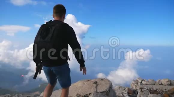 徒步旅行者带着背包到达山的边缘胜利地举起了他的手旅行期间男士积极休息视频的预览图