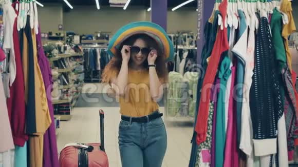 一位戴帽子的女士带着一个手提箱沿着商店走快乐的女性在商店购物视频的预览图