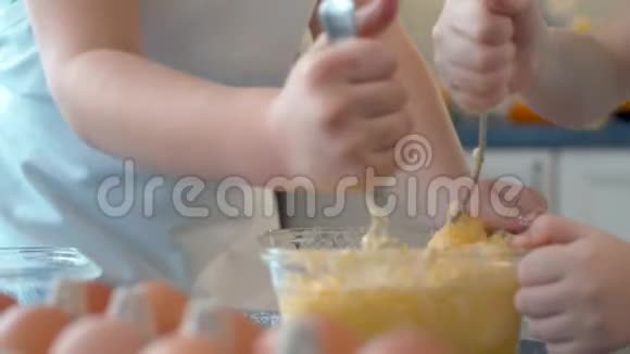 两个孩子的手把黄油和糖和鸡蛋混合在一起视频的预览图