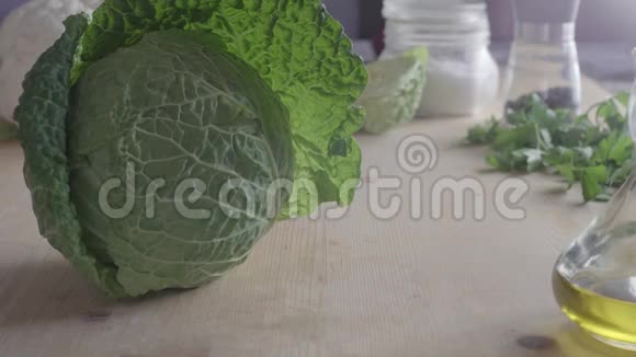 一个女人用的手在一个装有蔬菜的木制砧板上从外面的叶子上清理一棵美味的卷心菜的近景视频的预览图