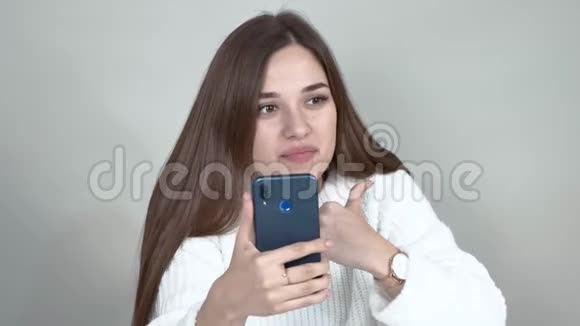 灰色背景白种人女孩博主棕色头发通过手机通讯视频的预览图
