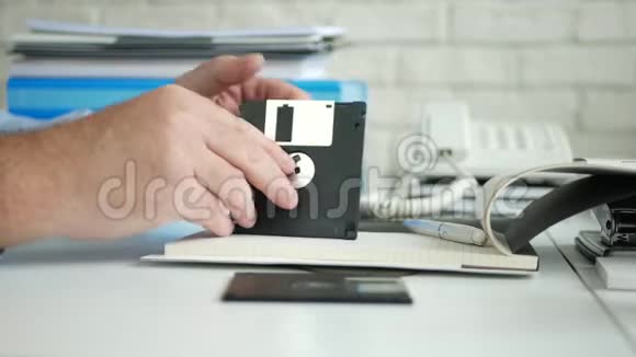 办公室里的人检查一个旧的存储设备一张用于计算机的软盘视频的预览图