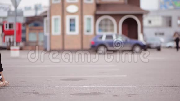一个穿着外套的年轻女人坐着儿童车在停车场里进出框架背景模糊视频的预览图