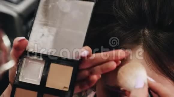 发型师在女孩额头上涂粉化妆程序视频的预览图