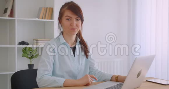 年轻迷人的白种人女医生用笔记本电脑在室内愉快地看着镜头特写照片视频的预览图