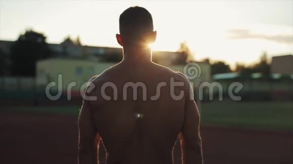 慢动作英俊的赤膊青年走向镜头的肖像身后有灿烂的阳光模糊的观点视频的预览图