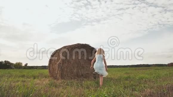 一个小女孩跑了而一堆稻草在田野里视频的预览图