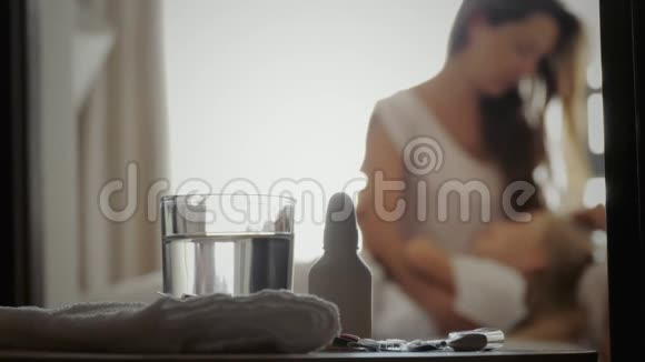 疾病概念母亲和生病的女儿在卧室里模糊的背景前景上的药品视频的预览图
