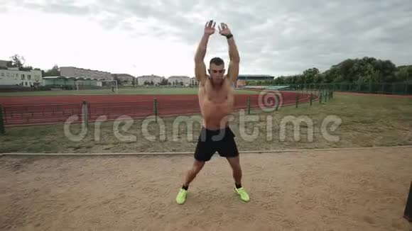 英俊的男运动员在户外体育场训练时做跳跃式的千斤顶练习视频的预览图