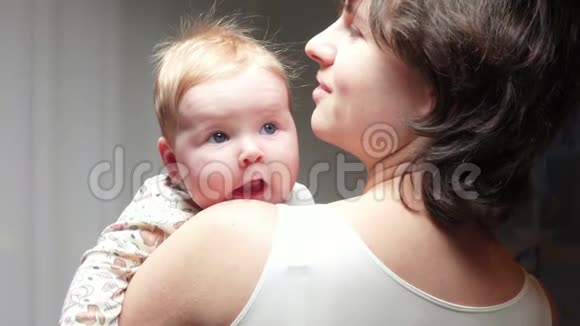 可爱的蓝眼睛小孩对着妈妈手臂微笑视频的预览图