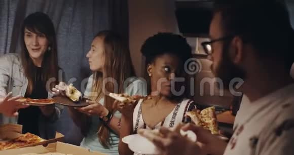 美丽的年轻多民族女性聊天微笑着吃披萨和朋友一起在厨房聚会上慢动作视频的预览图