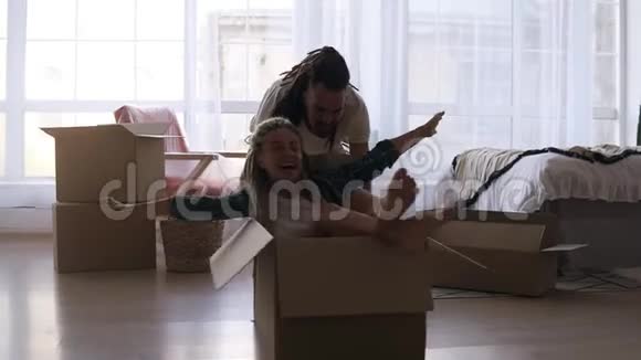 快乐时尚的夫妻在新房子里一起玩休息一下打开行李女孩骑着纸箱模仿视频的预览图