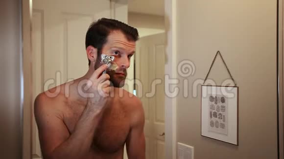 英俊的白种人年轻男子一边刮胡子一边看着浴室镜子里的自己HD24FPS视频的预览图