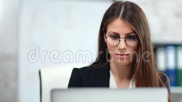 自信的欧洲女商人戴着律师眼镜簿记员在工作场所看着笔记本电脑屏幕视频的预览图