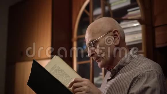 戴着皱纹和眼镜的智者翻阅着一本大书视频的预览图