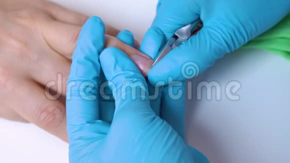 美甲师在美甲沙龙中去除和切割女性的角质层指甲护理视频的预览图