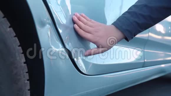一只雄性手在一辆破车的车门上摸索着一个凹痕检查裂缝和油漆碎片用手指按压评估损坏情况视频的预览图