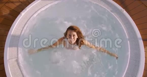 快乐的年轻女性模特在jucuzzi水中休息从上面看视频的预览图